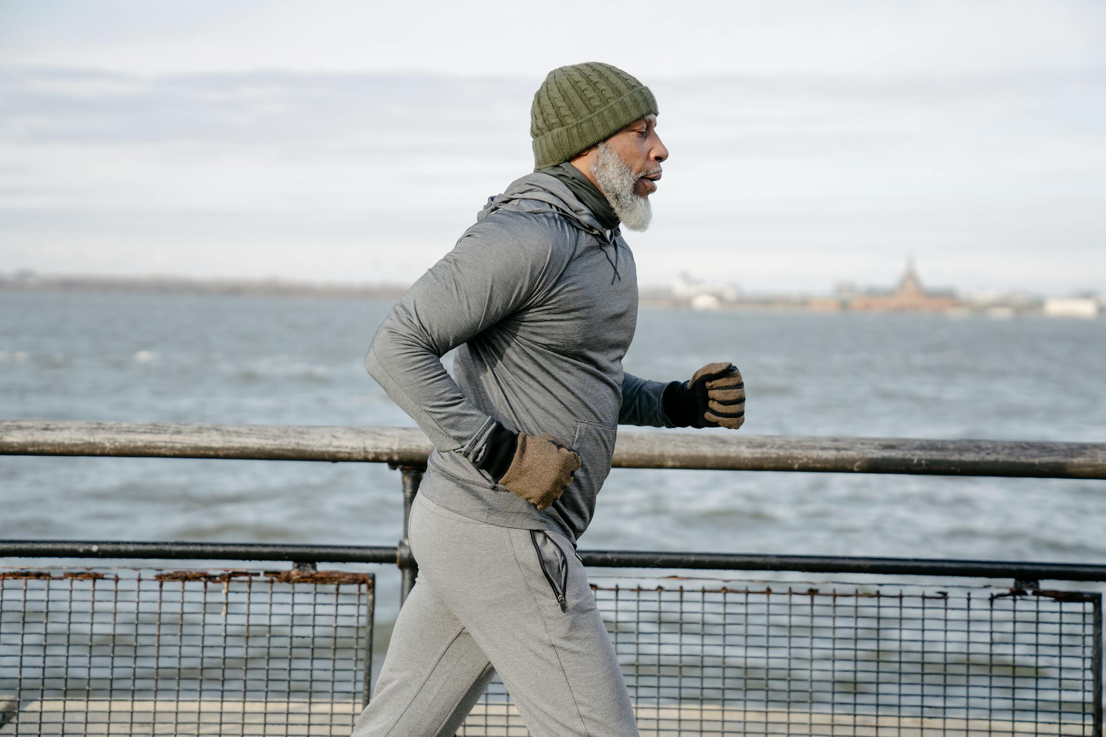 Person in winter gear jogging by a waterfront railing